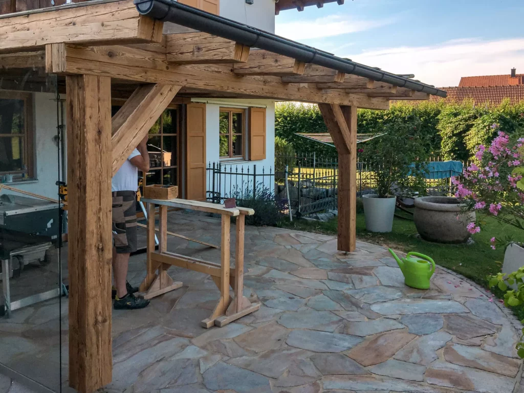 Außenbereich mit Altholzverbau und Terrasse aus Naturstein, Teil eines Wohnraumkonzepts mit maßgefertigter, Altholzmöbel