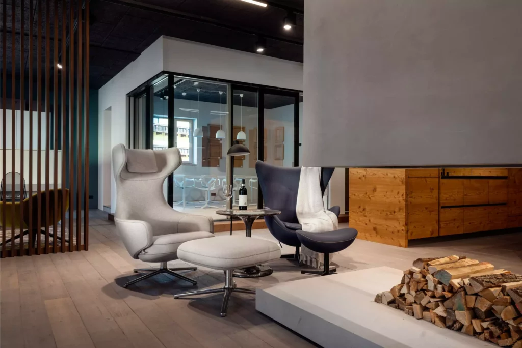 Moderner Showroom mit zwei Design-Sesseln, Hocker, Kaminholz und Holzfronten, stilvolle Innenarchitektur und Möbelstudio