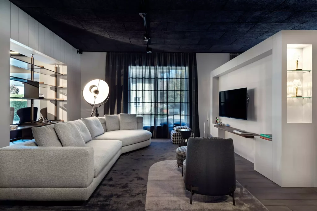 Moderner Showroom mit grauem Sofa, Designer-Sesseln, großem Stehlampenlicht, TV-Wand und maßgefertigter Innenarchitektur