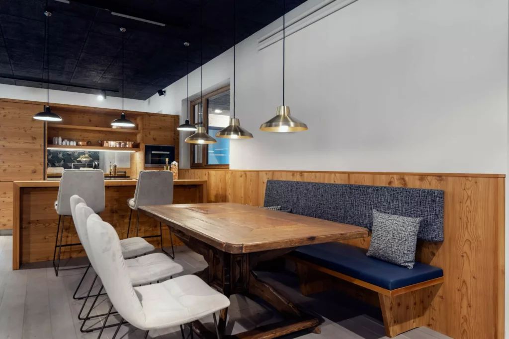 Moderner Showroom mit maßgefertigtem Holztisch, gepolsterten Stühlen, Bank mit blauer Polsterung und hängenden Lampen in