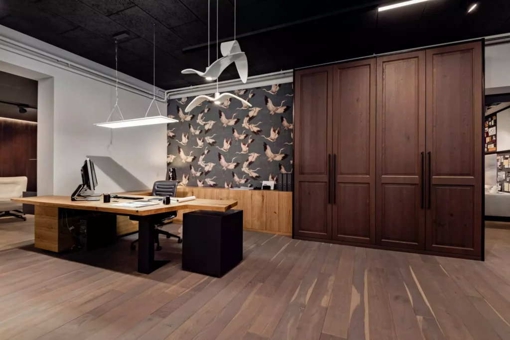 Moderner Showroom mit maßgefertigtem Holztisch, dunklem Holzschrank, Vogel-Tapete und Designerleuchten in Büroeinrichtung