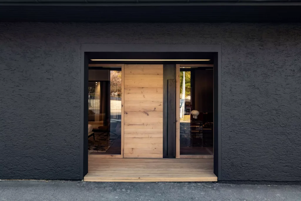 Moderner Showroom-Eingang mit großer Holztür und Glasfenstern in schwarzer Fassade, Möbelstudio Innenarchitektur