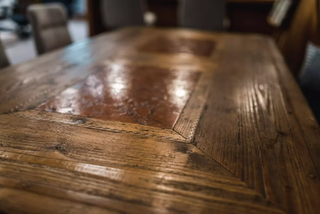 Nahaufnahme eines rustikalen Holztisches mit eingelassenen quadratischen Kupferplatten im Möbelstudio Showroom mit Fokus auf