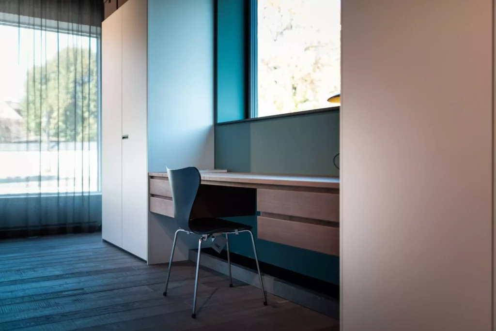 Moderner Showroom mit maßgefertigtem Holztisch und schwarzem Stuhl vor Fenster in stilvoller Innenarchitektur