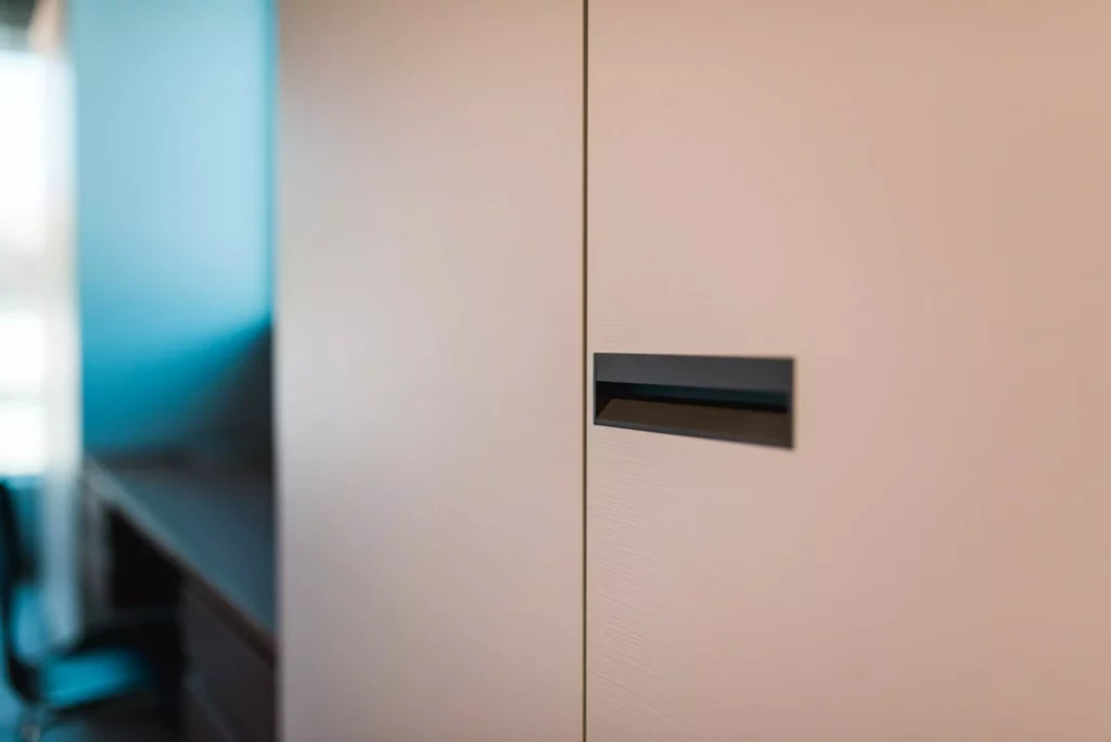 Nahaufnahme einer modernen, hellen Schranktür mit integriertem Griff im Möbelstudio Showroom, Innenarchitektur und