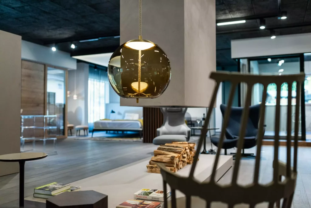 Moderner Showroom mit Designermöbeln, hängender Kugellampe, Kaminholz und Lounge-Sesseln im Möbelstudio M-Studio 2020