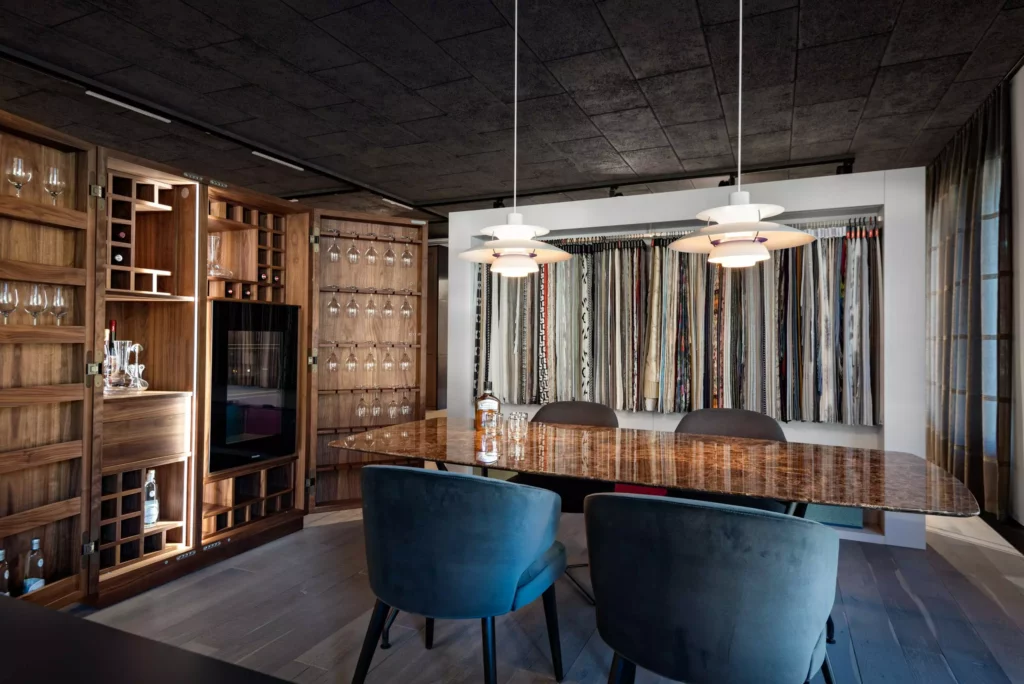 Moderner Showroom mit maßgefertigtem Holzmöbel, elegantem Tisch, Stoffmustern und Designerlampen in stilvoller