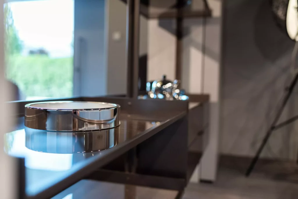 Moderner Showroom mit glänzendem Designermöbel und dekorativem silbernem Tablett auf dunkler Oberfläche in Möbelstudio