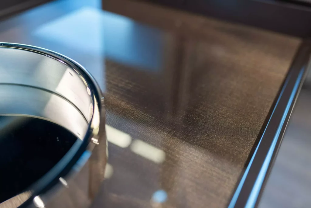 Nahaufnahme eines glänzenden Glastisches mit Metallrand im M-Studio Showroom, modernes Designermöbel mit feiner