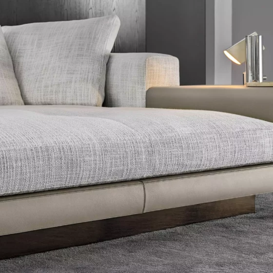 Modernes Minotti Sofa mit hellgrauem Stoffbezug und integriertem Seitentisch aus Leder im Möbelstudio Altenmarkt Salzburg