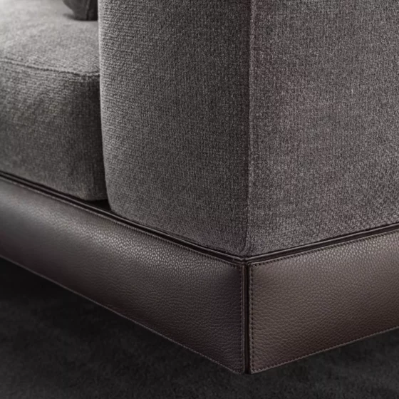 Nahaufnahme einer grauen Polstersofa-Ecke mit braunem Lederrahmen aus der Minotti Kollektion 2020 im Möbelstudio Reiter in