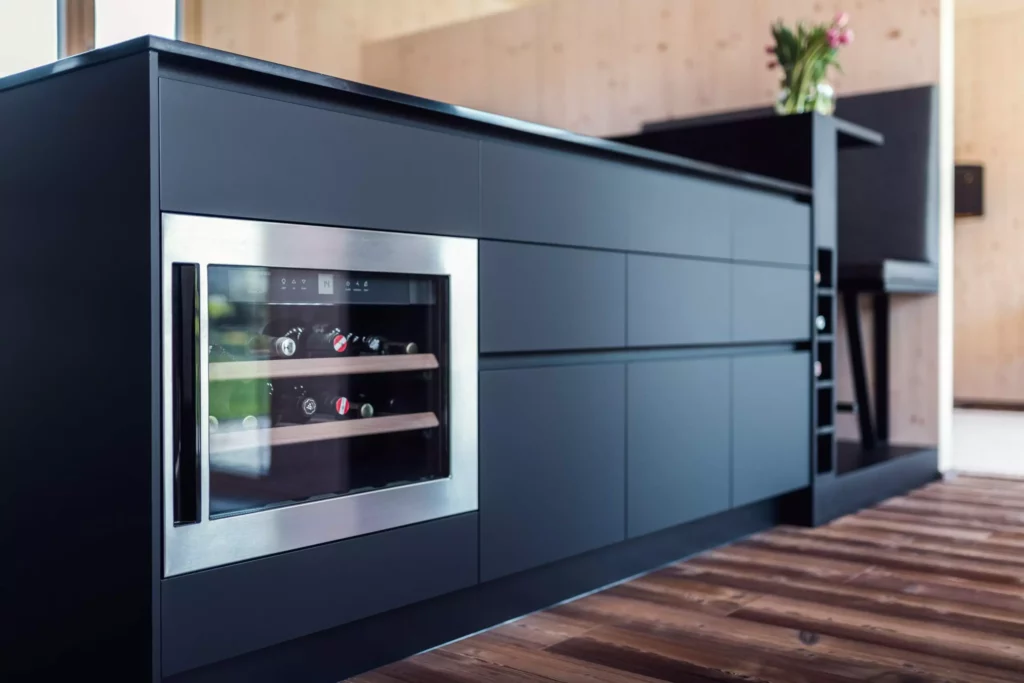 Moderne Poliform Küche in Salzburg mit integriertem Weinkühler, dunklen Fronten und Holzfußboden als Innenarchitektur