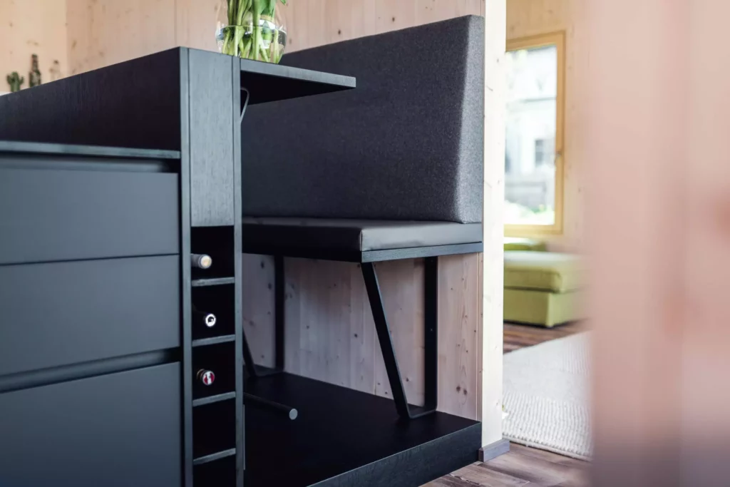 Schwarze Poliform Küche mit integriertem Sitzbereich und Weinregal vor hellem Holzpaneel in modernem Wohnraum mit