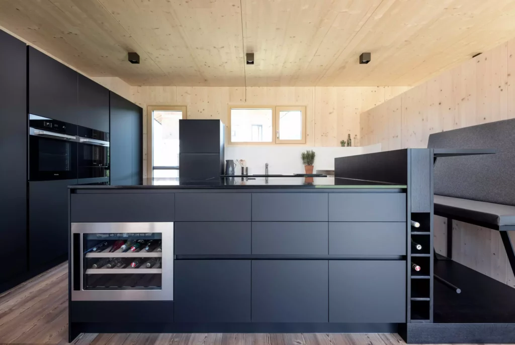 Moderne Poliform Küche in Salzburg mit schwarzer Kücheninsel, integriertem Weinkühler, Miele Geräten und Holzverkleidung für