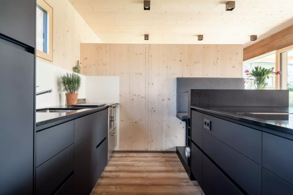 Moderne Poliform Küche in Salzburg mit schwarzer Alea Küchenzeile, Holzverkleidung, Bora Kochfeld und Sitzbank mit grauem