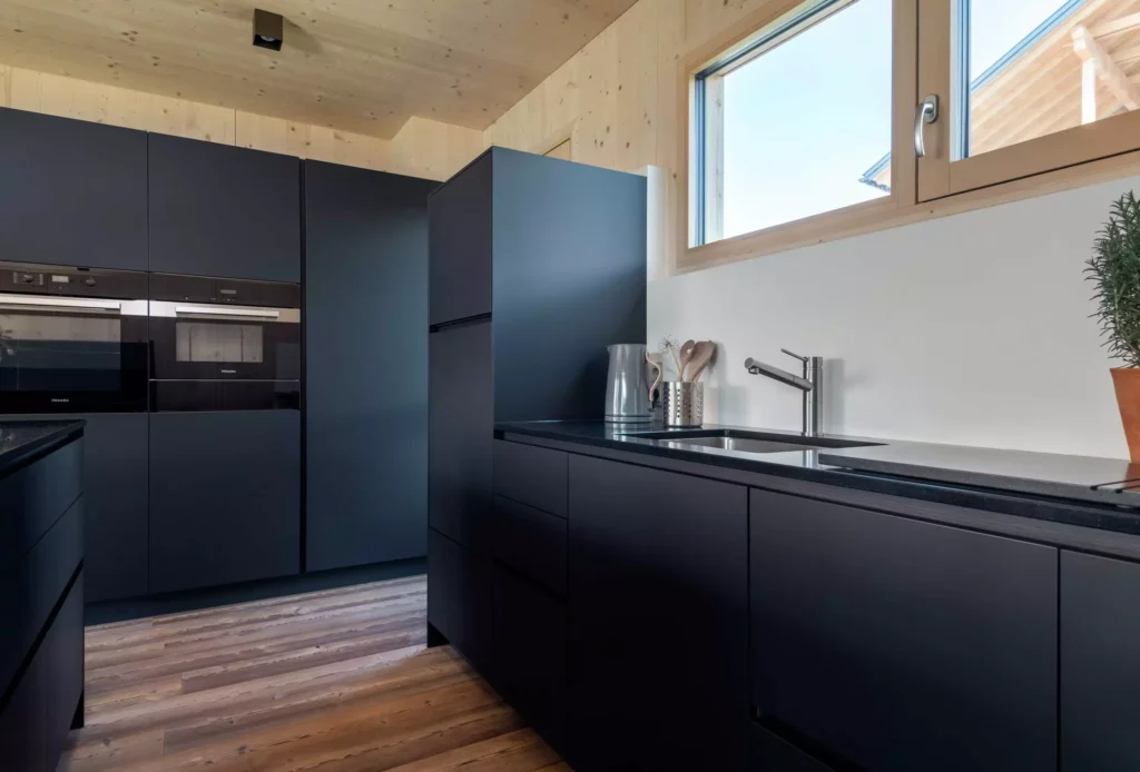 Moderne Poliform Alea Küche in mattem Schwarz mit Miele Geräten, Holzdecke und Fenster, hochwertige Innenarchitektur und