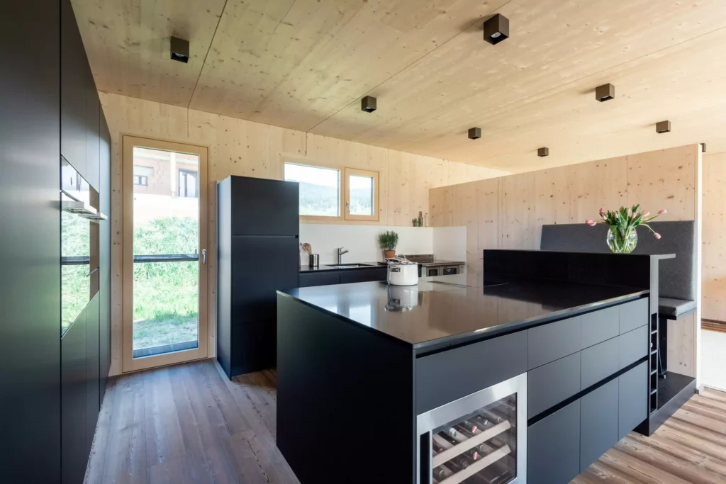 Moderne Poliform Küche Alea in Salzburg mit schwarzer Kücheninsel, Holzverkleidung, integriertem Weinkühler und Sitzbank mit