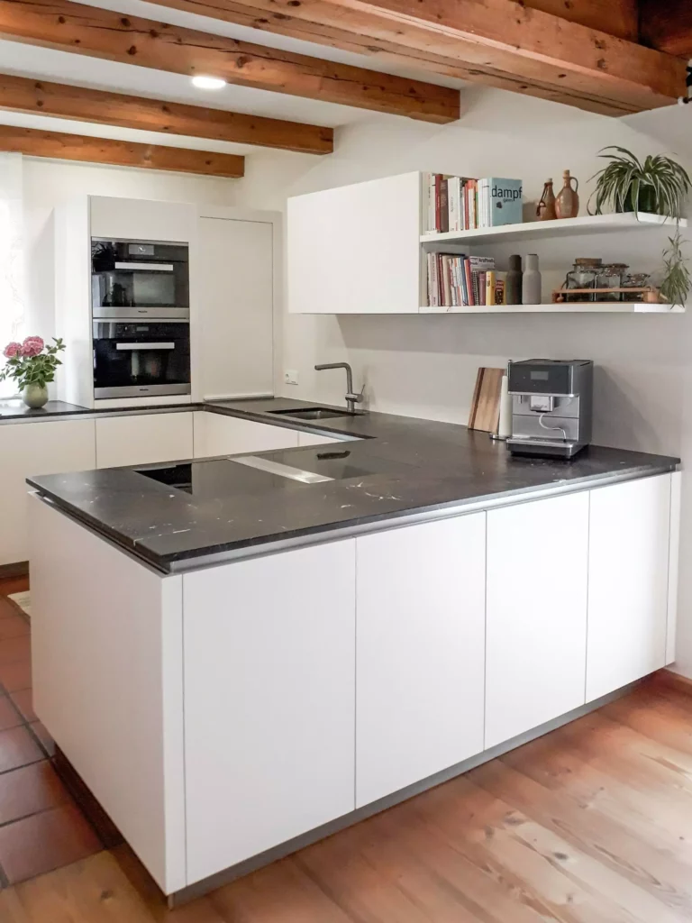 moderne weiße Küche mit schwarzer Arbeitsplatte, Einbaugeräten von Miele, offener Regalwand mit Büchern und, Selectiond