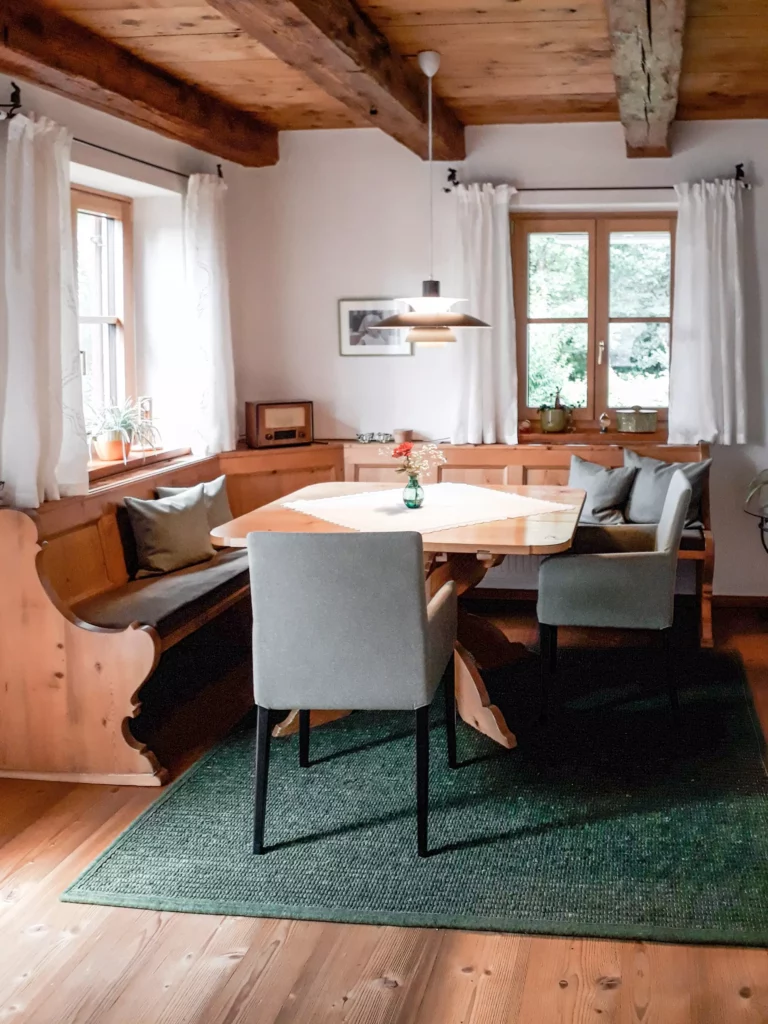 Essbereich mit maßgefertigter Eckbank aus Holz, grünem Teppich, zwei grauen Stühlen und Holztisch unter, Selectiond