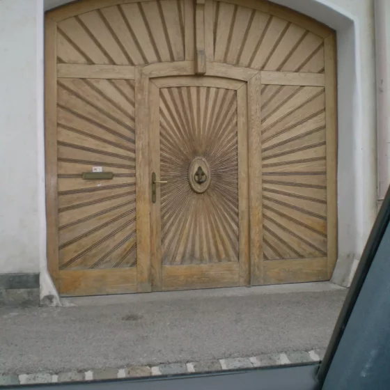 Holzgaragentor mit integrierter Tür und dekorativem Sonnenstrahlenmuster, gefertigt von Tischlerei Weitgasser in Altenmarkt