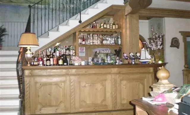 Holzbar mit Spirituosen und Gläsern unter einer Treppe in traditionellem Gastraum mit Lampen und Dekorationen, Weitgasser