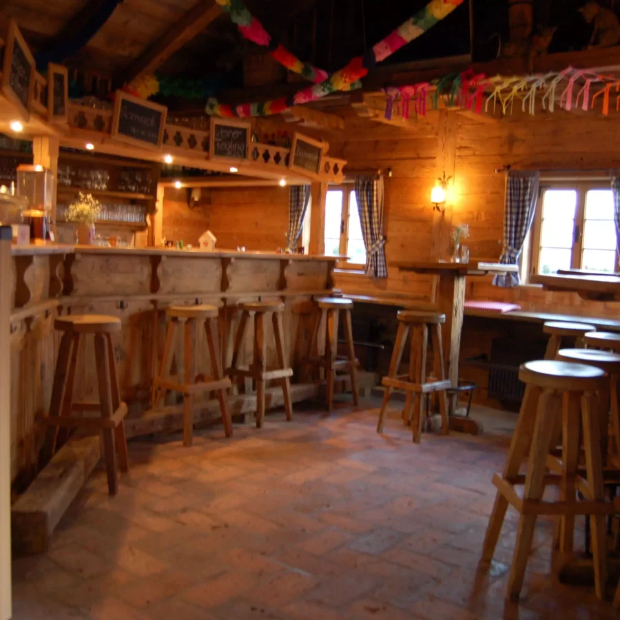 Rustikale Gastronomie mit maßgefertigten Holzhockern und Theke der Tischlerei Weitgasser in warmem Innenraum mit