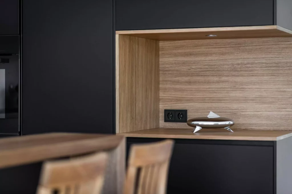 Moderne Tischlereiküche mit schwarzer Front, Holzarbeitsfläche, integriertem TV-Board und dekorativem, Tischlerküche