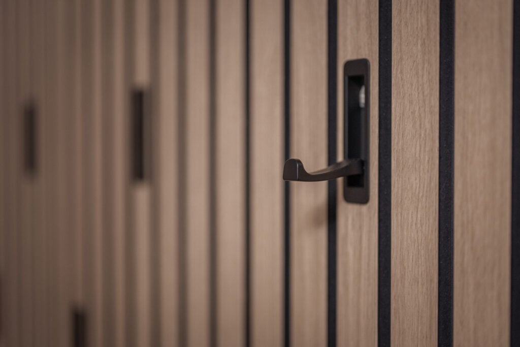 Nahaufnahme eines modernen Holzschranks mit schwarzen Griffen und vertikalen schwarzen Linien als Designelement, Einrichtung