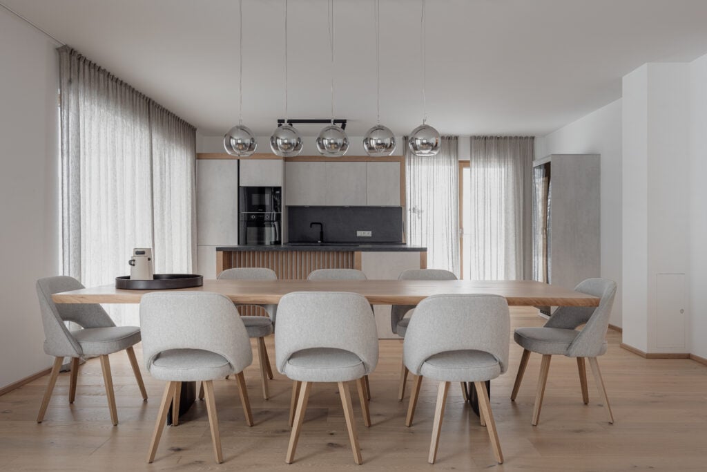 Moderner Essbereich mit maßgefertigtem Holztisch, grauen Polsterstühlen und minimalistischer Küche im, Einrichtung