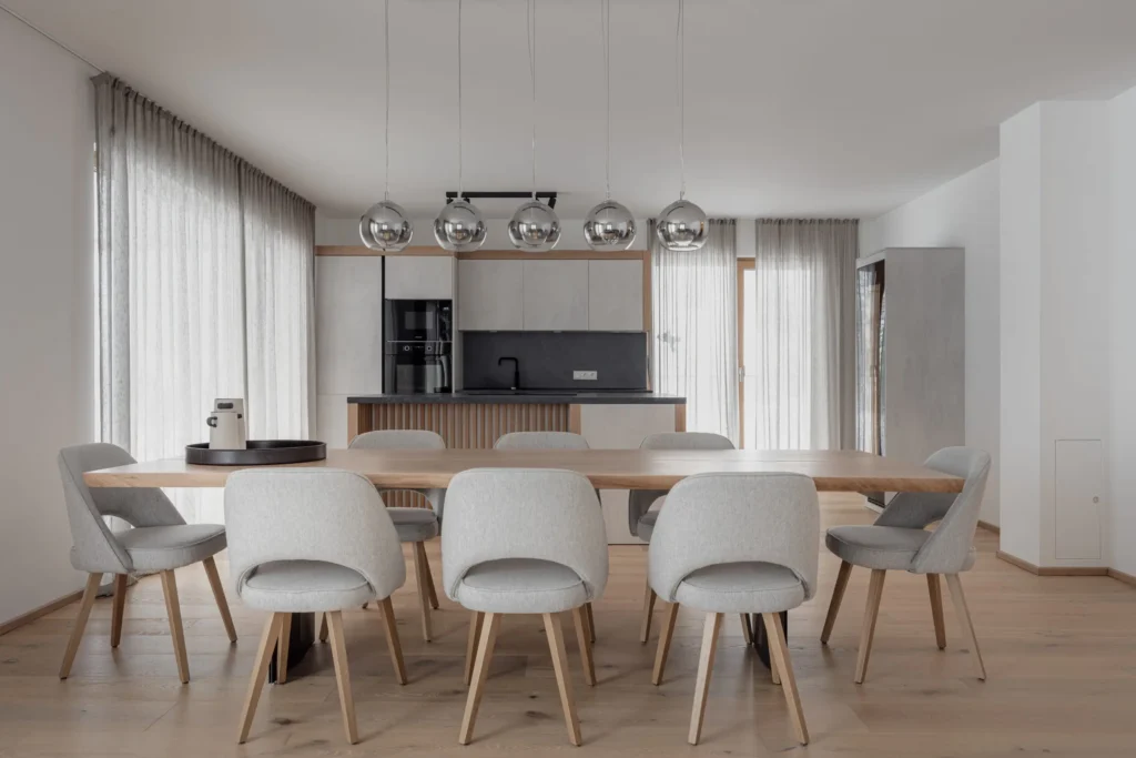 Moderner Essbereich mit maßgefertigtem Holztisch, grauen Polsterstühlen und minimalistischer Küche im, Einrichtung