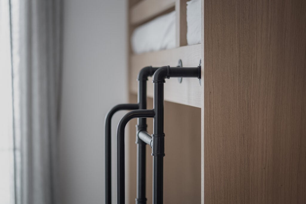 Detailaufnahme eines maßgefertigten Etagenbetts aus Holz mit schwarzen Metallgeländern in einem Zweitwohnsitz, Einrichtung