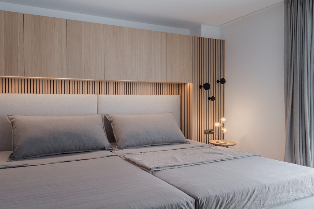 Modernes Schlafzimmer mit maßgefertigtem Holzpaneel, integriertem Stauraum, grauer Bettwäsche und indirekter, Einrichtung