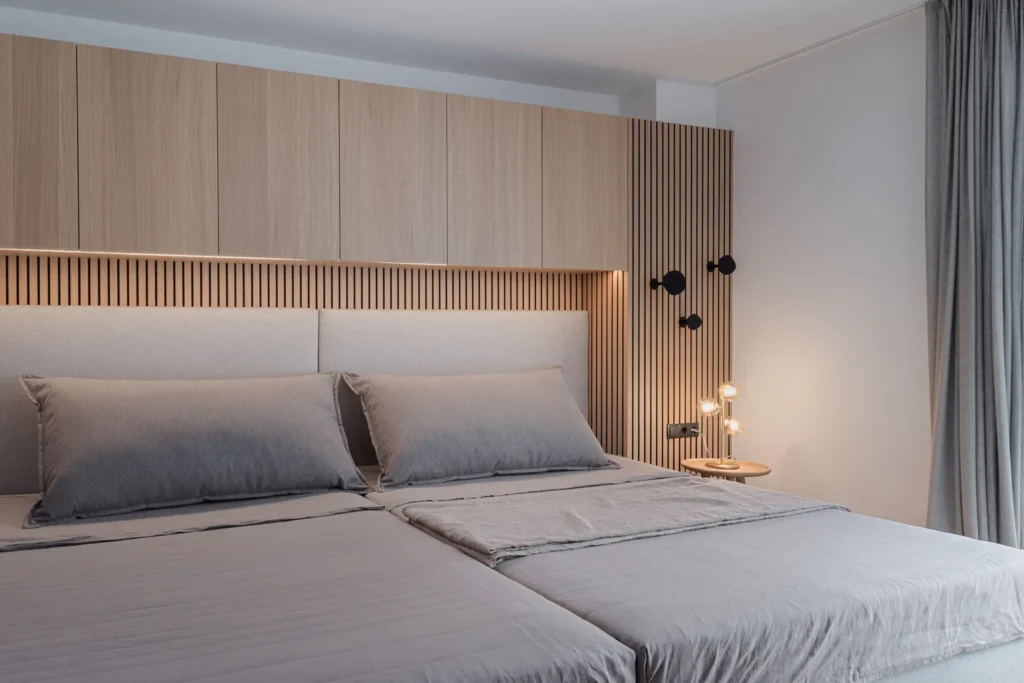 Modernes Schlafzimmer mit maßgefertigtem Holzpaneel, integriertem Stauraum, grauer Bettwäsche und indirekter, Einrichtung
