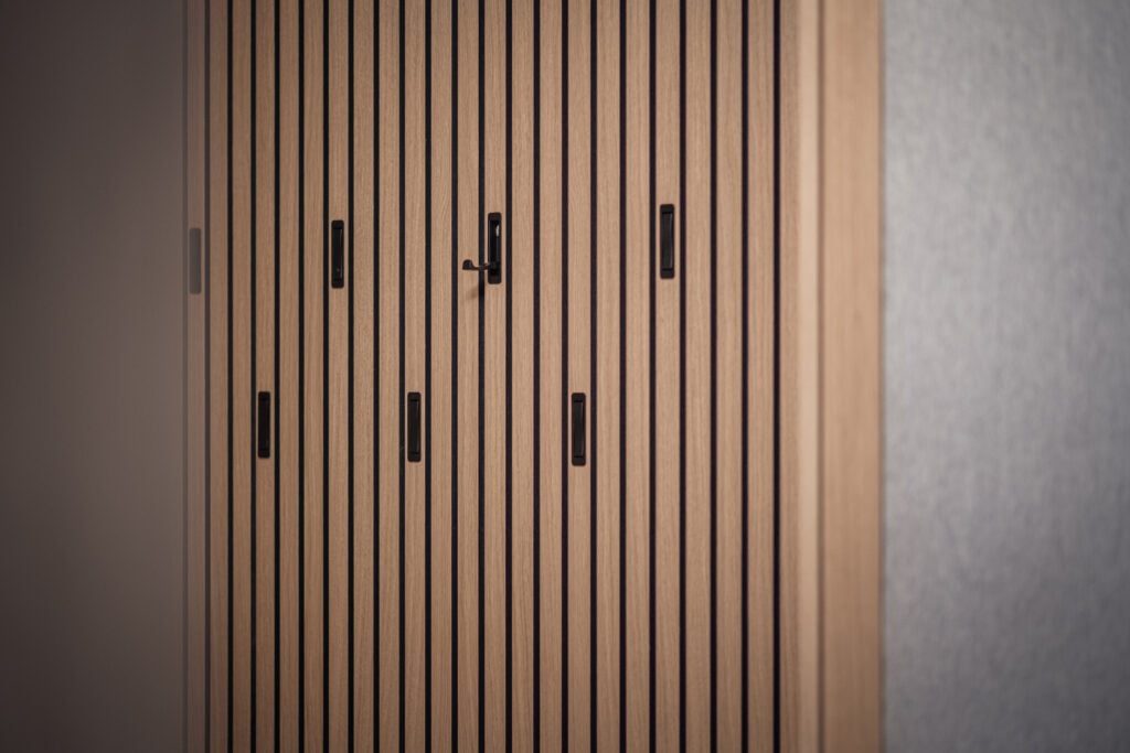 Maßgefertigte Holzschiebetüren mit vertikalen Lamellen und schwarzen Griffen in einem Zweitwohnsitz in Salzburg, Einrichtung