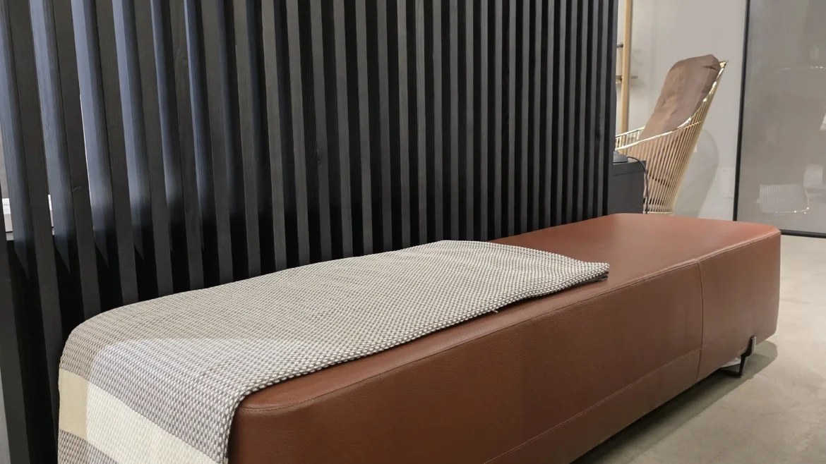 Braune Lederbank mit grauer Decke vor schwarzer Lamellenwand im modernen Möbelstudio Showroom, Scaled