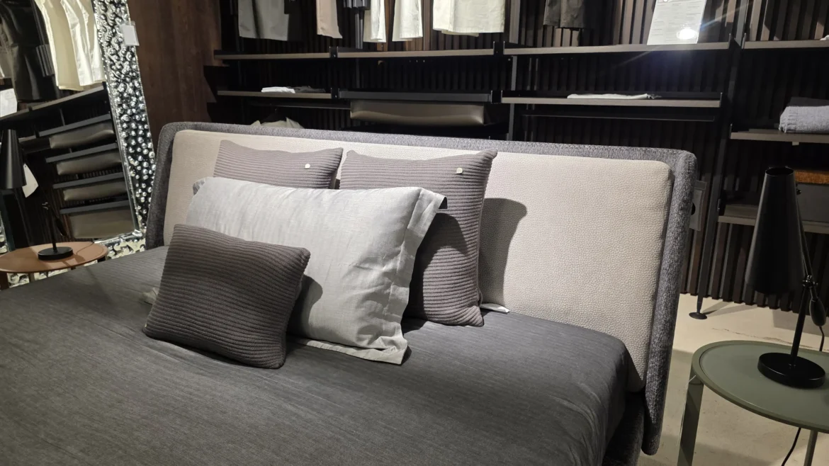 Minotti Bett mit grauer Bettwäsche und Kissen im modernen Showroom für Innenarchitektur und Designermöbel