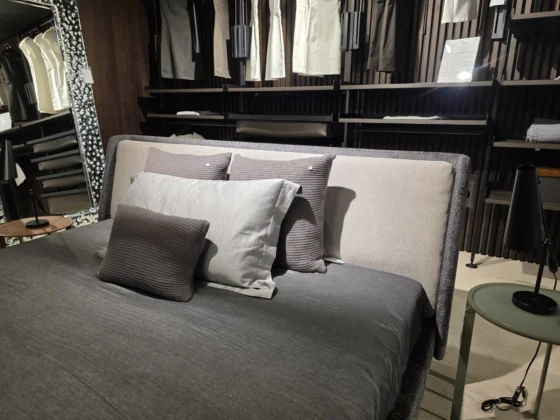 Minotti Bett mit grauer Bettwäsche und Kissen im modernen Showroom für Innenarchitektur und Designermöbel
