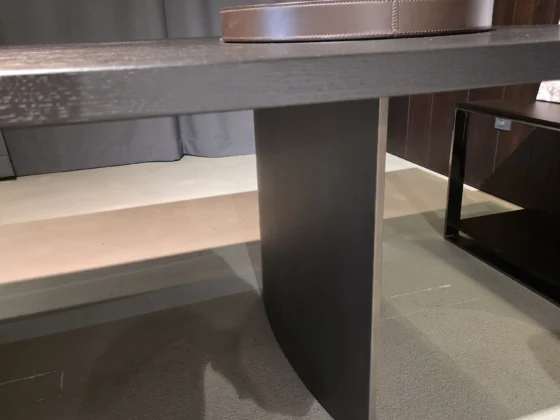 Moderner Minotti Linha Tisch mit dunkler Holzplatte und zentralem Metallfuß in elegantem Showroom-Interieur