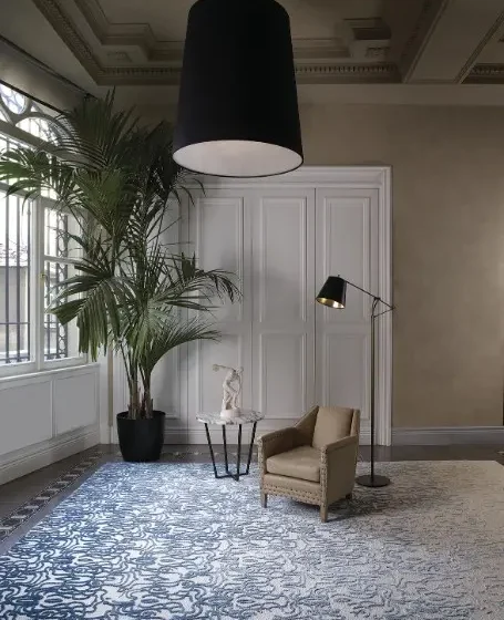 Moderner Wohnraum mit Stepevi Teppich Fade, Ledersessel, Stehlampe, Beistelltisch und großer Zimmerpflanze im Showroomstil