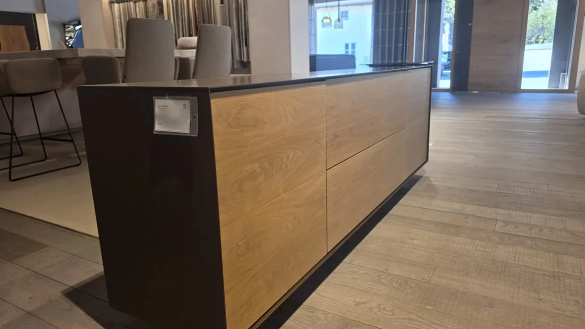 Moderner Holz- und Metall-Sideboard im Möbelstudio mit Stühlen und Stoffmustern im Hintergrund