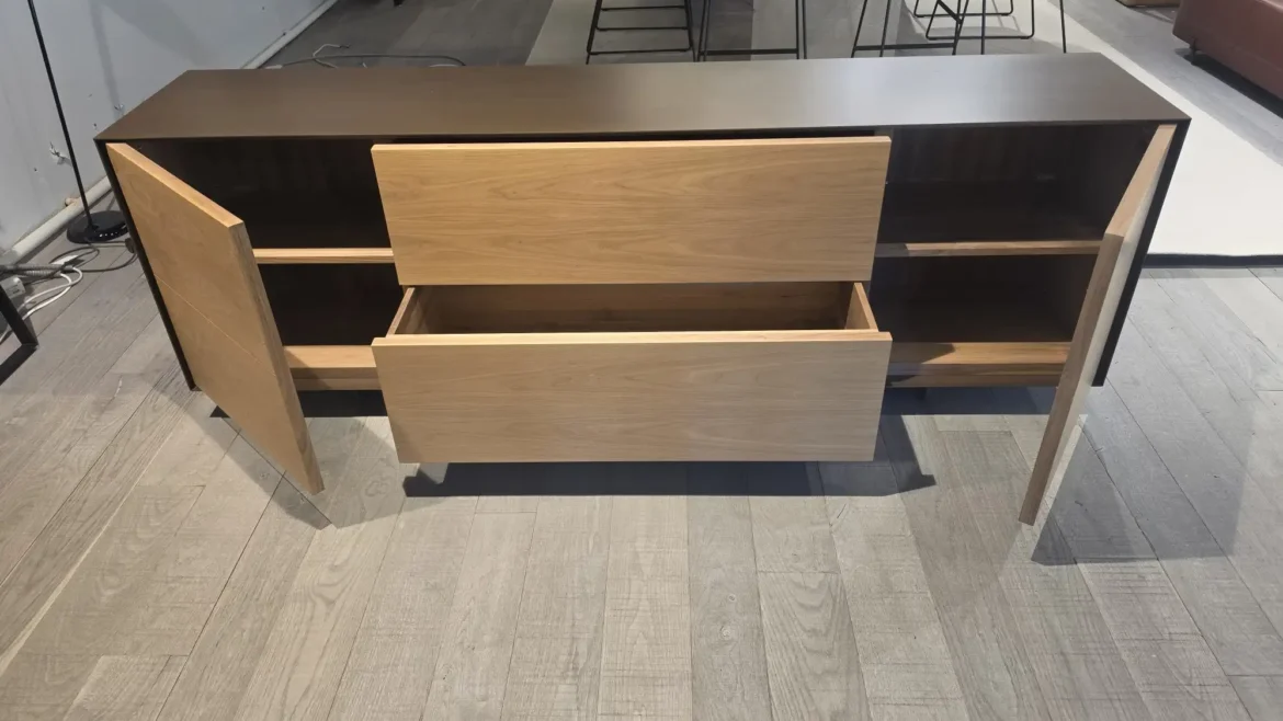 Sideboard mit geöffneten Holztüren und Schubladen in modernem Möbelstudio mit Holzfußboden und Stühlen im Hintergrund