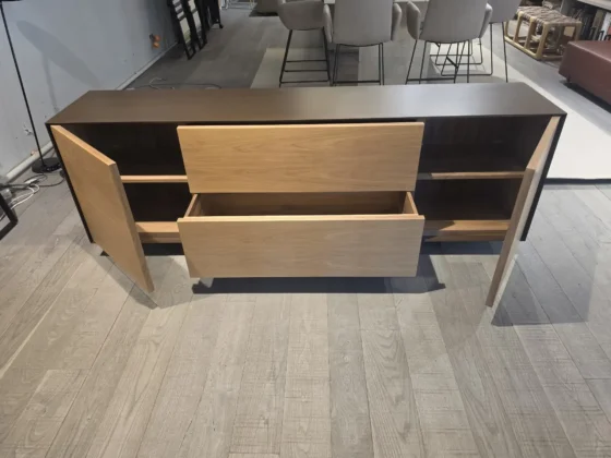 Sideboard mit geöffneten Holztüren und Schubladen in modernem Möbelstudio mit Holzfußboden und Stühlen im Hintergrund