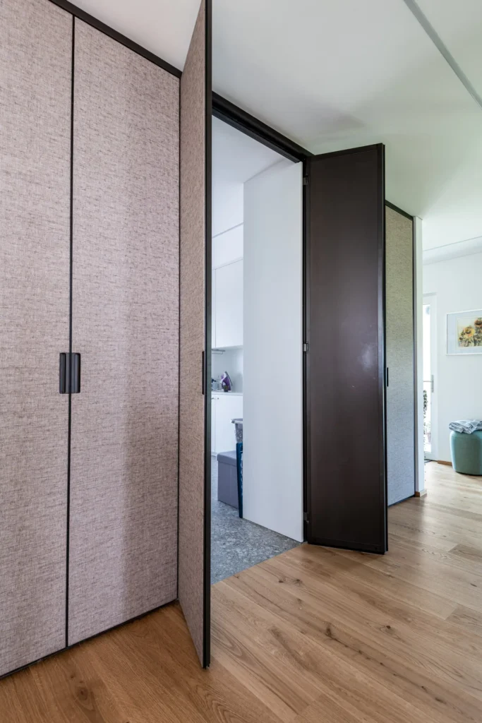 Modernes Rimadesio Schranksystem mit Stofffronten und integrierter Tür in hellem Wohnraum mit Holzboden